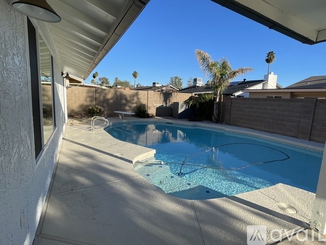 A pool with a white fence and a house in the background.