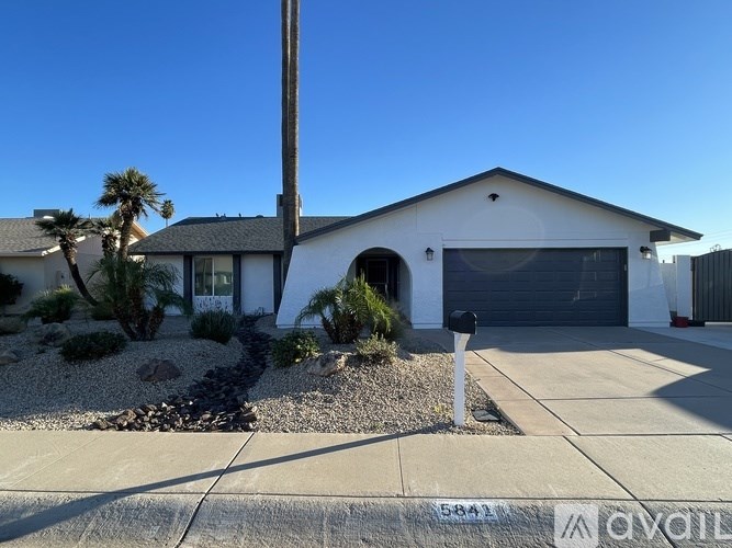 A white house with a garage door and a driveway in front.