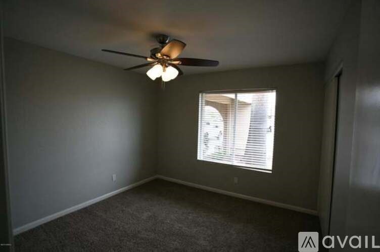 A room with a ceiling fan and a window with blinds.