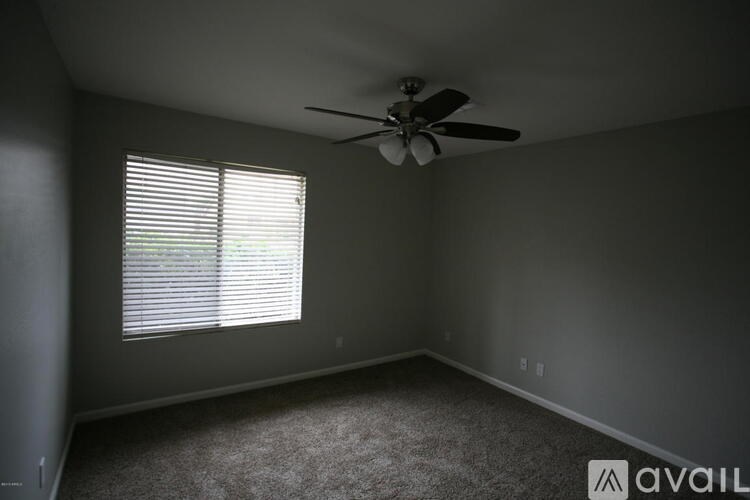 A room with a ceiling fan and a window with blinds.