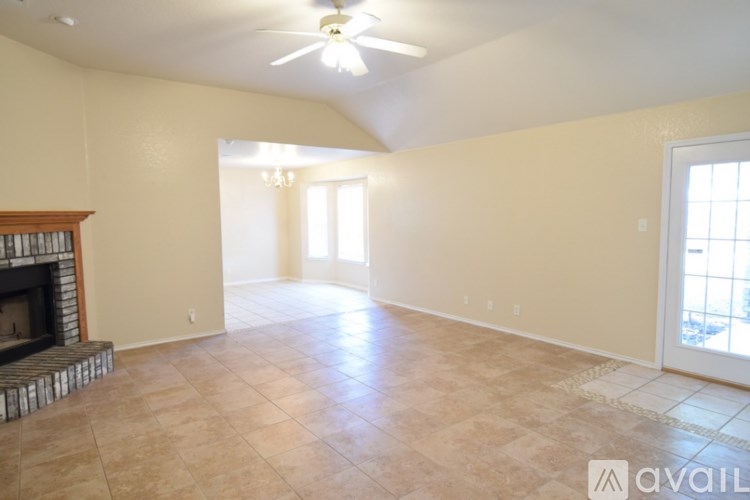 A spacious room with a fireplace and a ceiling fan.