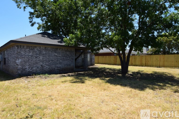 A tree stands in a grassy field in front of a small building.