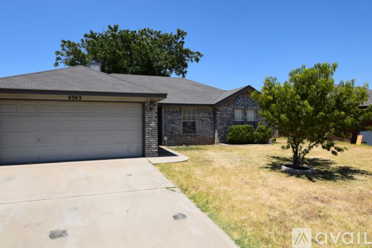 A house with a garage and a tree in front.