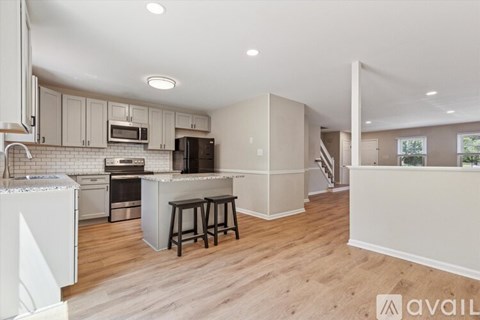A kitchen with white cabinets and a wooden floor.