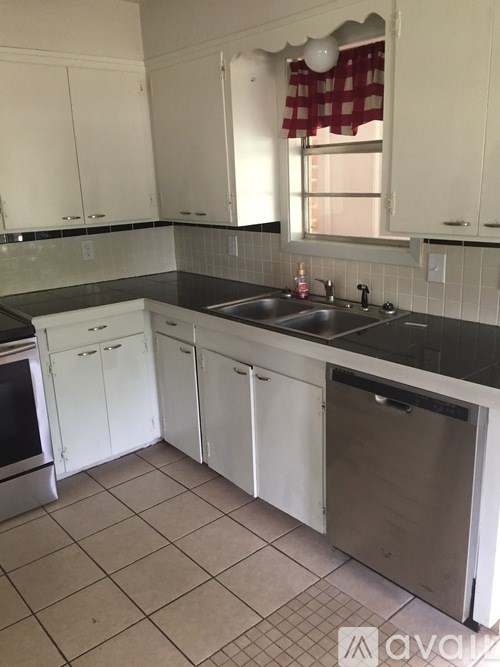 A kitchen with white cabinets and a black countertop.