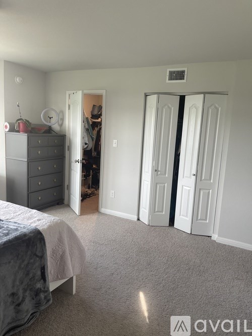 A bedroom with a bed, dresser, and two doors.