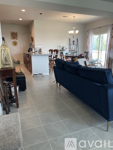 A living room with a dark blue couch and a white kitchen in the background.