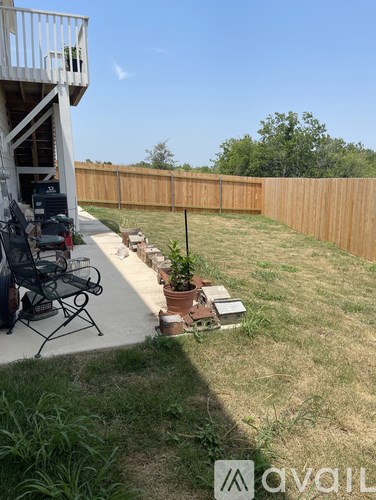 A backyard with a wooden fence and a small tree in a pot.