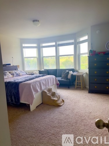 A bedroom with a bed, a chair, and a dresser.