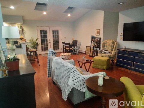 A living room with a couch covered in a white blanket and a television on the wall.