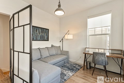 A living room with a grey couch and a wooden floor.