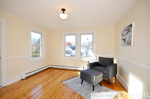 A living room with a grey chair and ottoman.