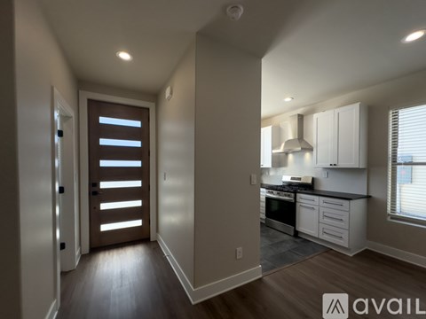 A modern kitchen with white cabinets and a wooden floor.
