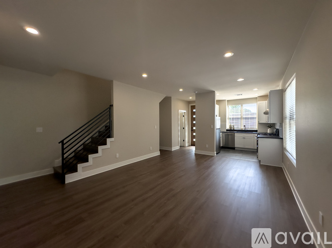 A spacious living room with hardwood floors and a staircase leading to the upper level.
