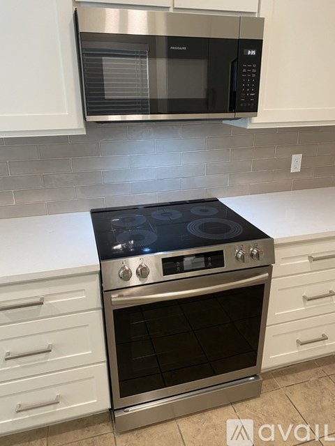 A modern kitchen with a stainless steel oven and white cabinets.