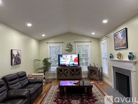 A living room with a black leather couch and a television on a wooden stand.