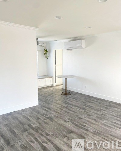 A room with a grey floor and a white wall with a plant on it.