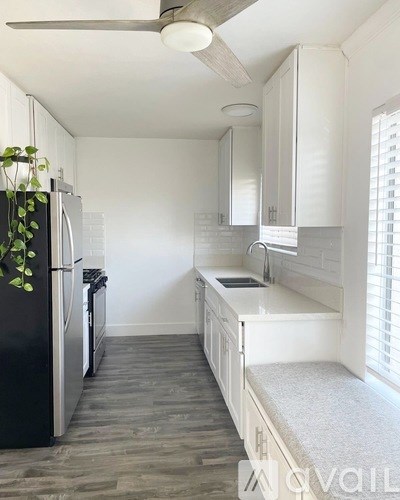 A kitchen with white cabinets and a black fridge.
