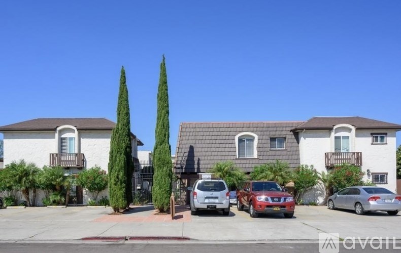 A row of houses with cars parked in front.