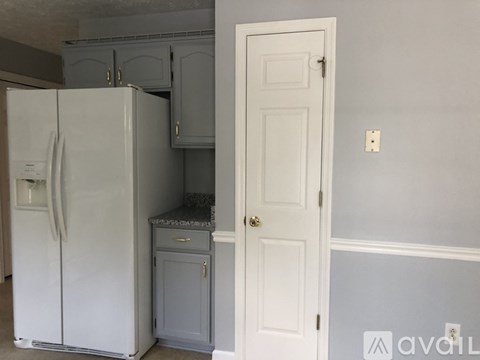 A white refrigerator is in a kitchen with a white door.