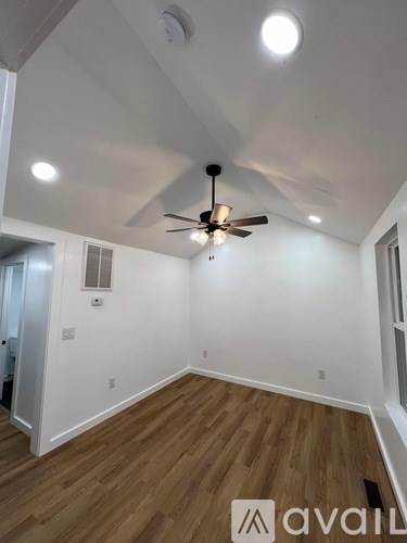 A room with a ceiling fan and wooden flooring.