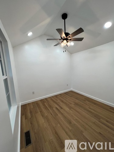 A room with a ceiling fan and wooden flooring.