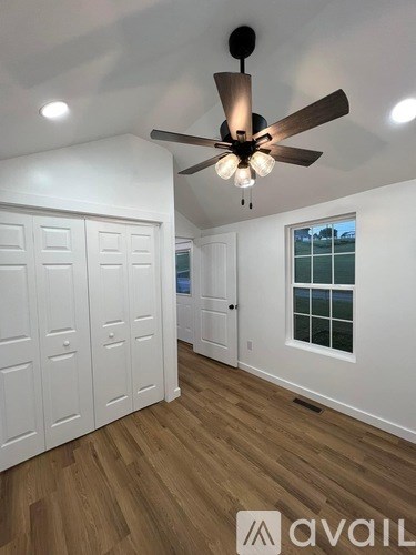 A room with a ceiling fan and wooden floors.