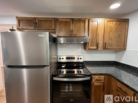 A kitchen with a stainless steel refrigerator and a stove with a black countertop.