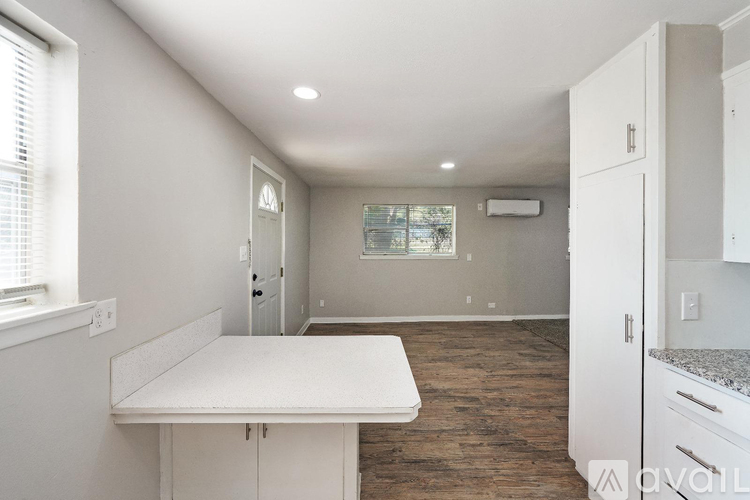 A kitchen with a white countertop and wooden flooring.