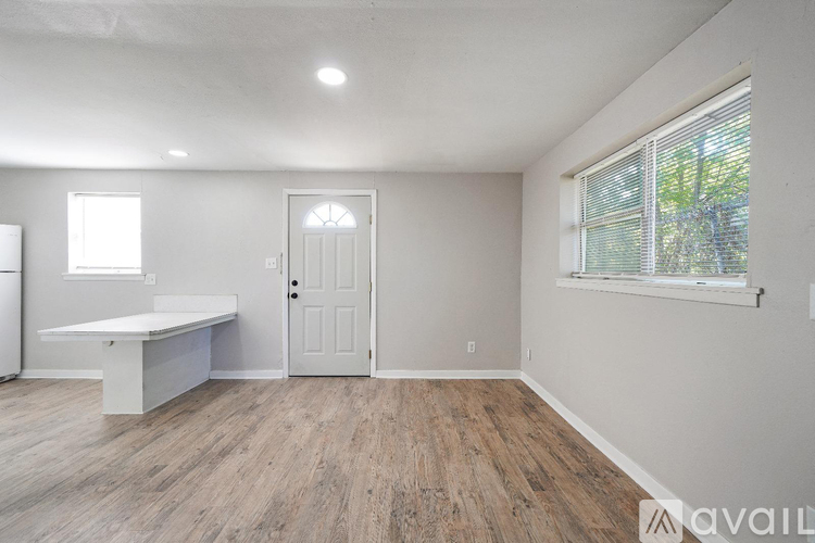 A room with a white door, a window with blinds, and a white table.