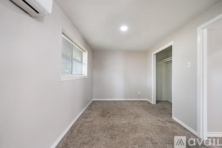 A room with a carpeted floor and a window with blinds.