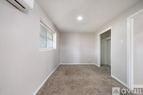 A room with a carpeted floor and a window with blinds.
