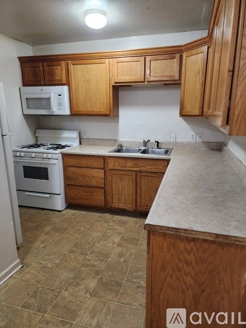 A kitchen with wooden cabinets and a tiled floor.