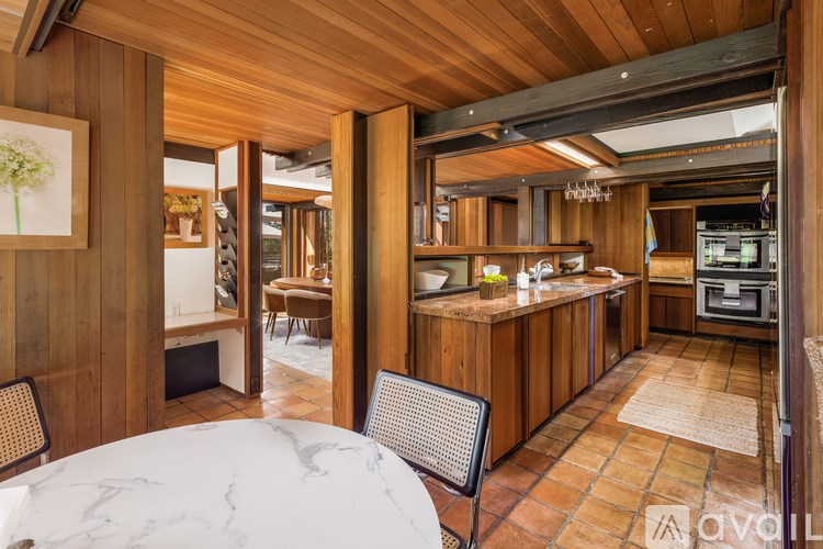 A modern kitchen with wooden cabinets and a marble table.