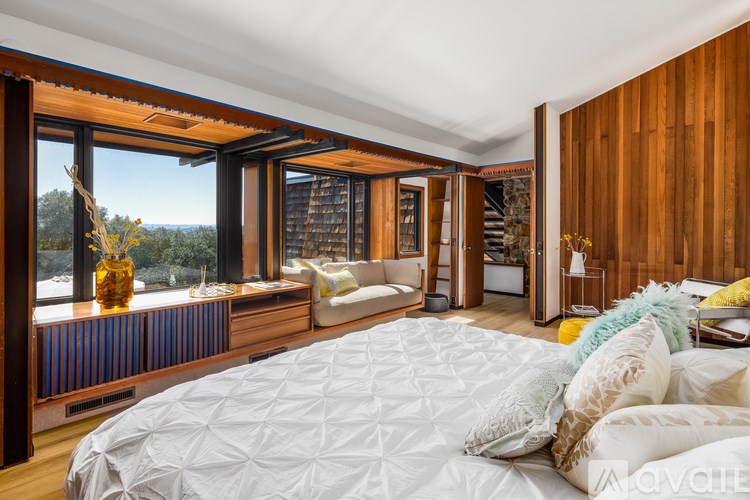 A bedroom with a large bed and a view of the trees outside the window.