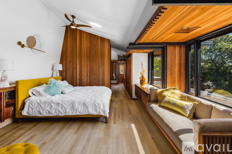 A bedroom with a bed and a couch with a window in the background.