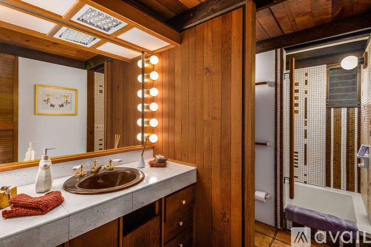 A bathroom with a wooden vanity and a mirror with lights.
