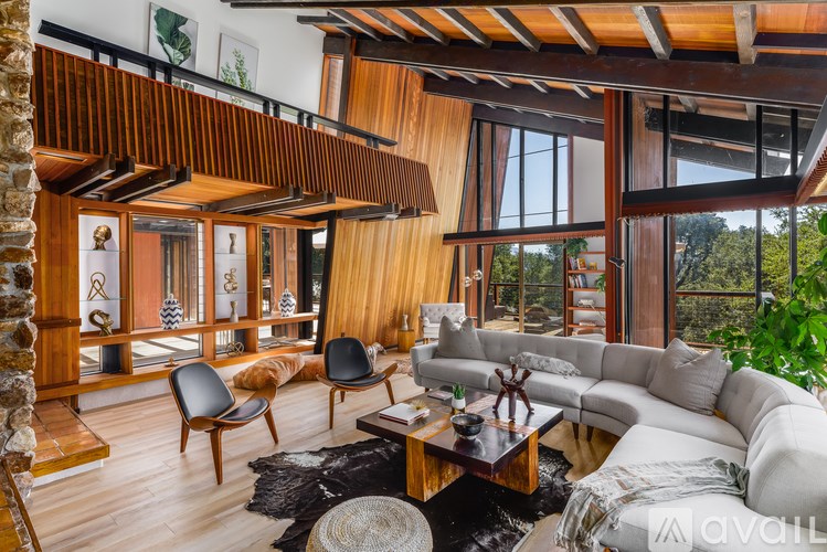 A modern living room with a wooden ceiling and a large window.
