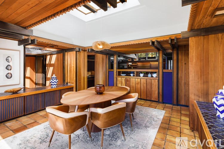 A wooden dining room with a round table and chairs.
