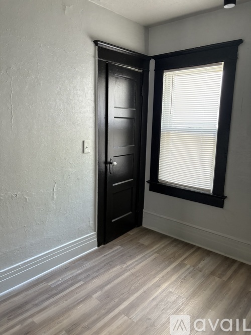 A room with a black door and a window with blinds.