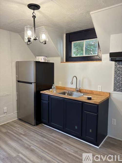 A kitchen with a black fridge and a wooden counter top.