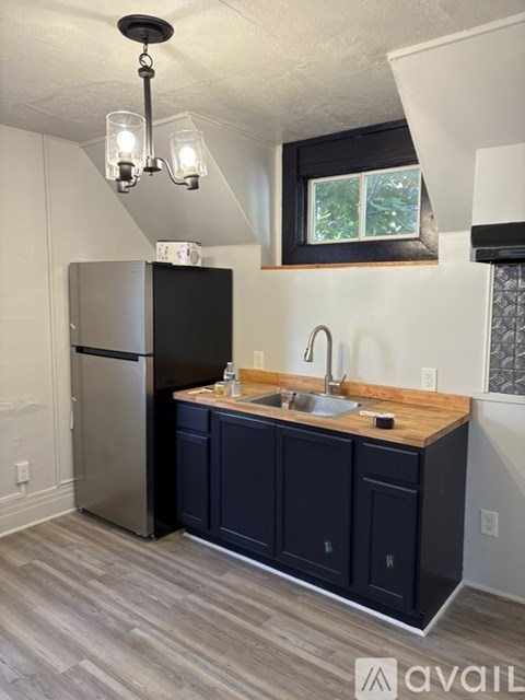 A kitchen with a black fridge and a wooden counter top.
