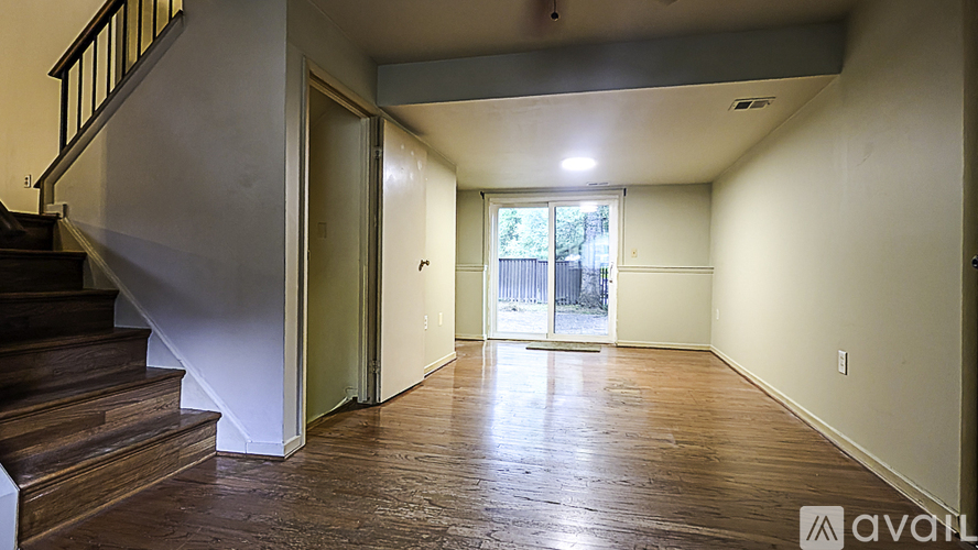 A spacious room with wooden floors and a staircase leading to the upper level.