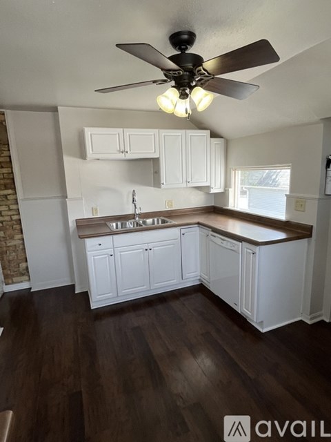 A kitchen with white cabinets and a ceiling fan.