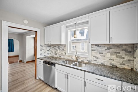A kitchen with white cabinets and a granite countertop.