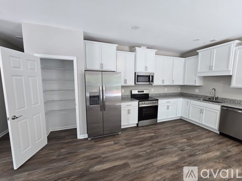 A kitchen with white cabinets and a wooden floor.