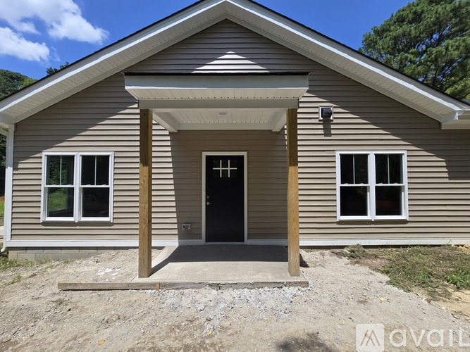 A house with a brown siding and a black door is for sale.