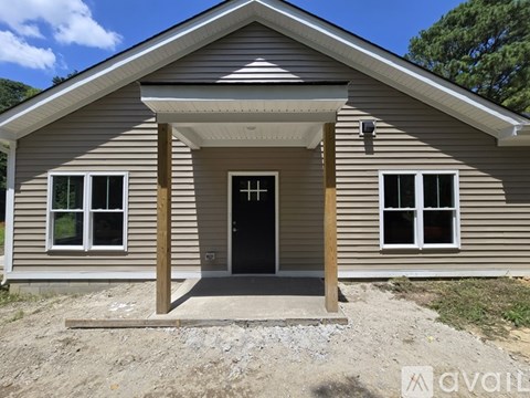 A house with a brown siding and a black door is for sale.