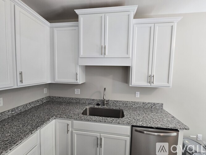 A kitchen with white cabinets and a granite countertop.