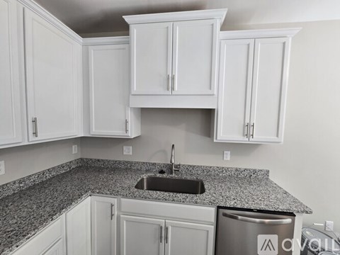 A kitchen with white cabinets and a granite countertop.